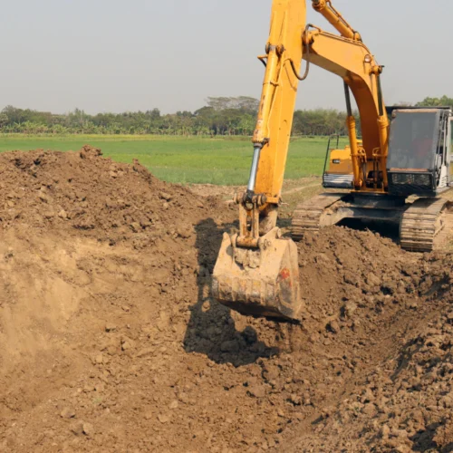 yellow excavation machine picking up some dirt
